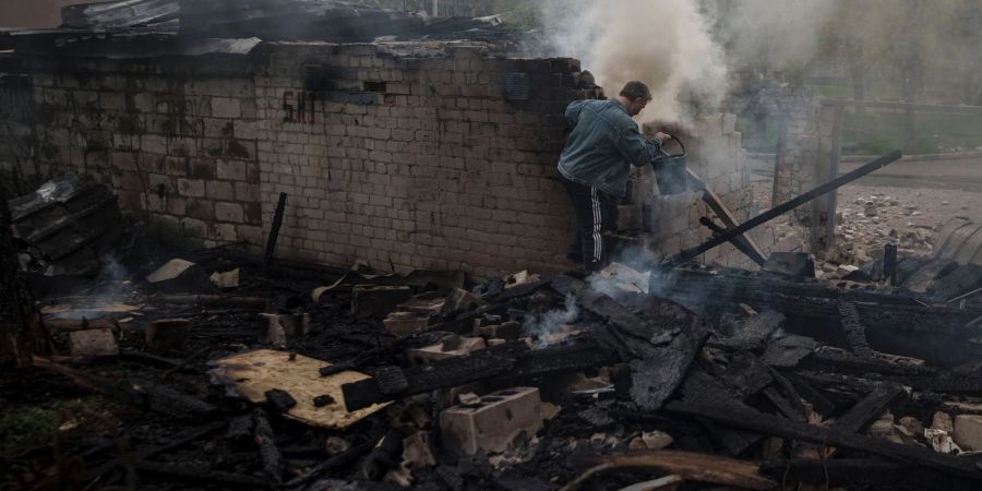 Ein Mann versucht, nach einem russischen Bombardement eines Wohnviertels in Charkiw, ein Feuer zu löschen.