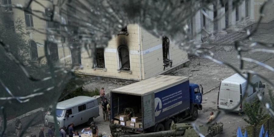 Anwohner stehen in Lyssytschansk für humanitäre Hilfe an - neben ihnen vom russischen Militär erbeutete ukrainische Panzer und Waffen. Dieses Bild wurde während einer vom russischen Verteidigungsministerium organisierten Reise aufgenommen. Foto: Uncredited/AP/dpa