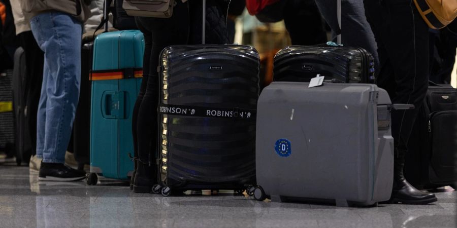 Passagiere mit Koffern warten am Check-In Schalter am Frankfurter Flughafen.