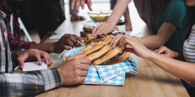 freunde greifen gemeinsam nach brezeln, küchentisch