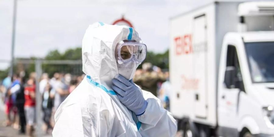 Ein Bundeswehr-Soldat im Schutzanzug und mit Mund-Nasenschutzmaske in Verl. Dort stehen mehrere Mehrfamilienhäuser, in denen Werkvertragsarbeiter der Firma Tönnies leben, unter Quarantäne. Foto: David Inderlied/dpa