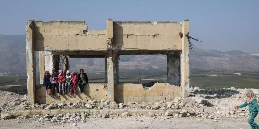 Kinder spielen in den Trümmern einer zerstörten Schule. Foto: Anas Alkharboutli/dpa