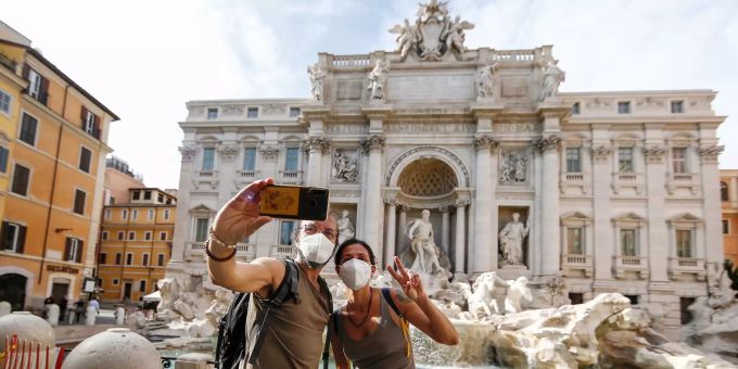 Ein Paar mit Schutzmasken macht ein Selfie vor dem Trevi-Brunnen. Coronavirus - Italien