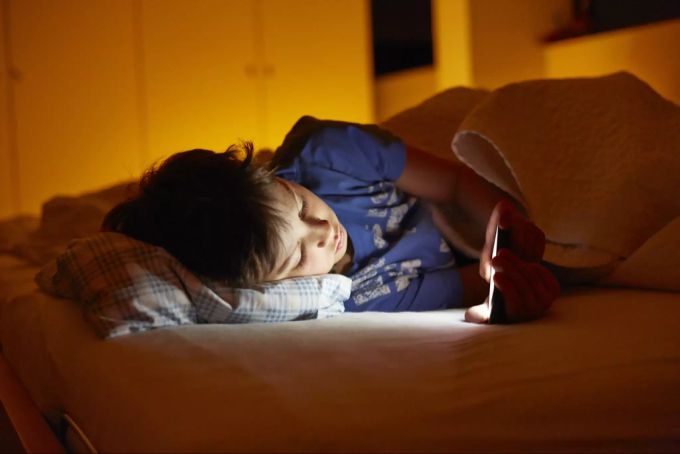 Besonders vor dem zu Bett gehen sollten Eltern trotzdem eine Beschränkung der Bildschirmzeit einführen. Kinder Smartphone
