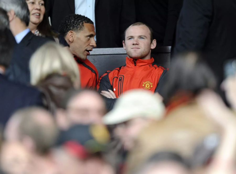 Rio Ferdinand (l.) und Wayne Rooney sitzen gemeinsam auf der Bank von Manchester United. (Archivbild)