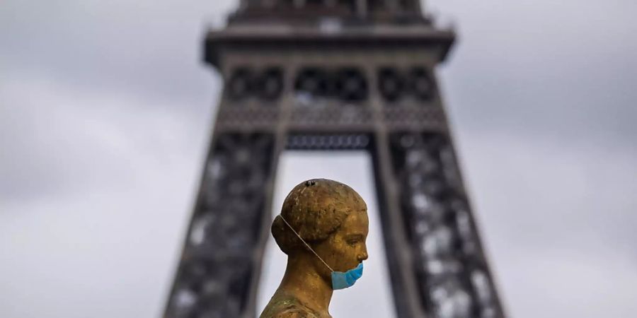 Eine goldene Statue am Pariser Platz Trocadéro trägt eine Schutzmaske. Im Hintergrund ist das berühmte Wahrzeichen Eiffelturm zu sehen. (Archivbild)