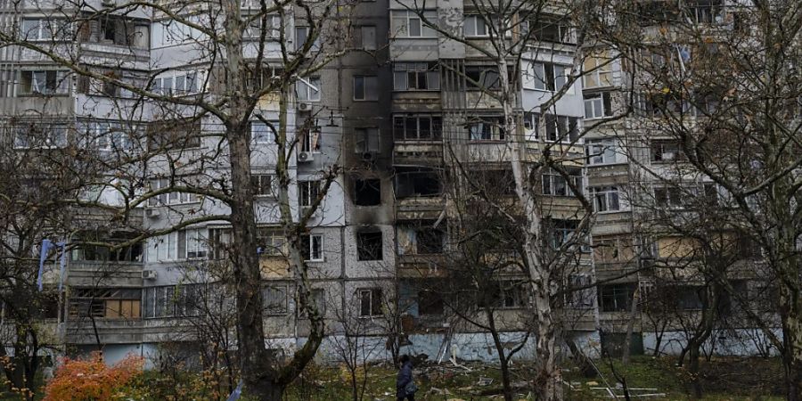 Eine Frau geht in Cherson an einem kürzlich durch einen Angriff beschädigten Gebäude vorbei. Foto: Bernat Armangue/AP/dpa