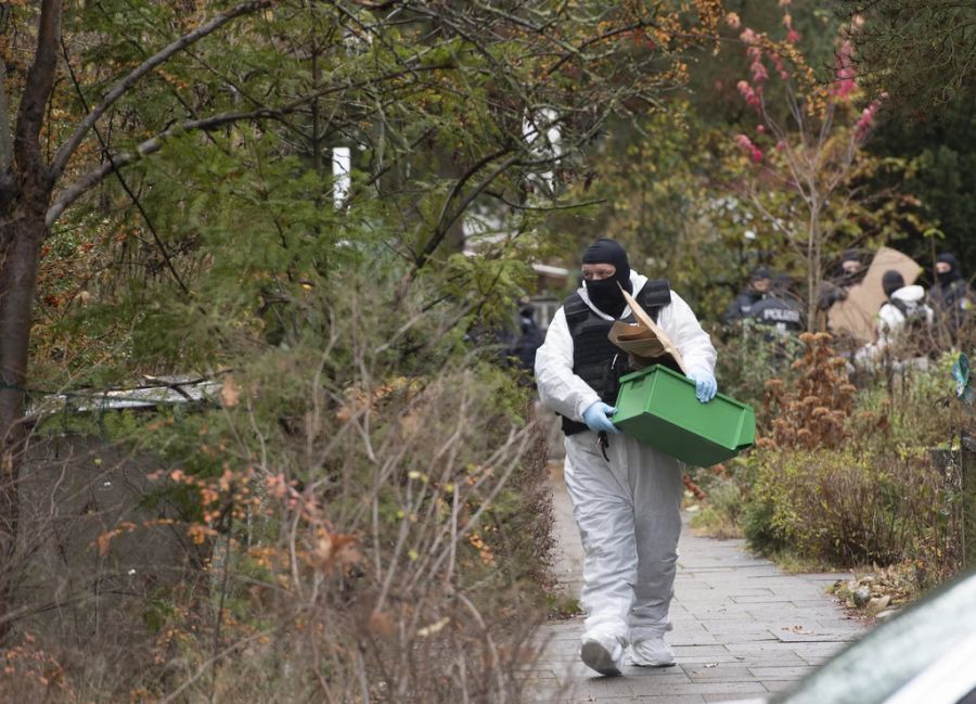 Ein Mitarbeiter der Spurensicherung trägt eine Kiste bei Ermittlungen in Berlin Wannsee.