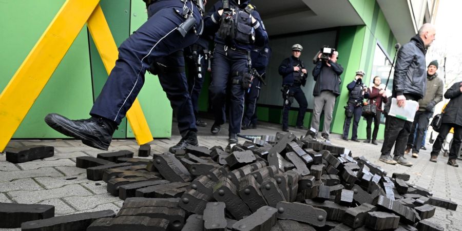 Polizisten gehen über einen Kohlehaufen, den Aktivisten verschiedener Umweltschutzgruppen vor der Grünen Parteizentrale in Nordrhein-Westfalen hingeworfen haben.