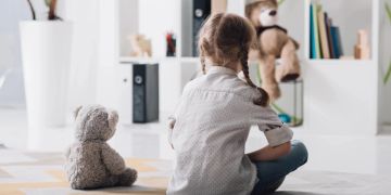 kind und teddy sitzen auf dem boden