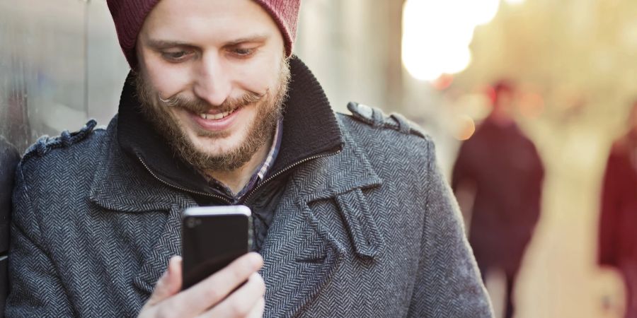 Mann mit Smartphone lächelt