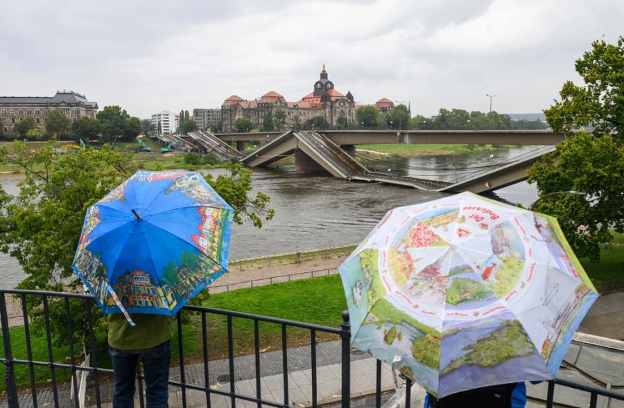 Passanten blicken auf die eingestürzte Carolabrücke in Dresden.