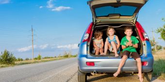 Drei Kinder in einem Kofferraum, Urlaub mit dem Auto.