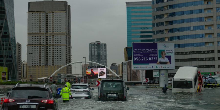 Fahrzeuge stecken nach heftigen Regenfällen auf einer überfluteten Straße fest, während ein Lieferwagen abgeschleppt wird. Foto: Uncredited/AP/dpa