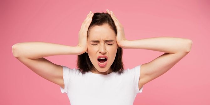 Frau hält sich die Hände über die Ohren. Stress.