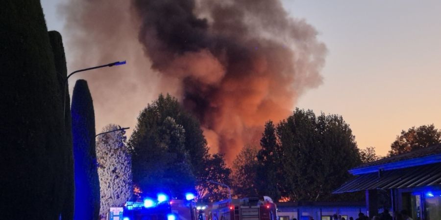 Eine große Rauchwolke von einem Brand ist auf einem Campingplatz am Gardasee zu sehen. Einsatzkräfte der Feuerwehr sind vor Ort. Bei dem großen Brand sind mehr als 20 Menschen verlet...