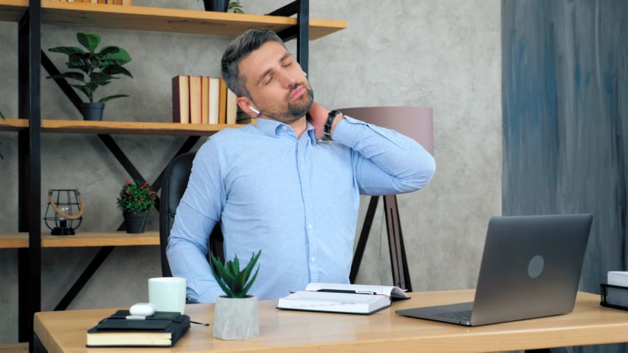 mann, reibt sich schmerzenden nacken, bürotisch