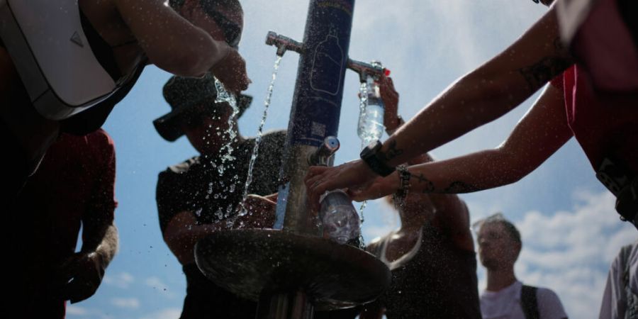 ARCHIV - Touristen erfrischen sich an einem öffentlichen Trinkbrunnen in Paris. Foto: Christophe Ena/AP/dpa/Symbolbild