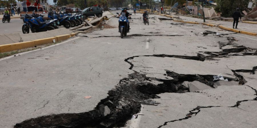 Motorradfahrer fahren auf einer Straße, die durch die Erdbeben, die La Guaira in Venezuela einen Tag zuvor erschüttert hatten, aufgerissen wurde. Foto: Javier Campos/AP/dpa