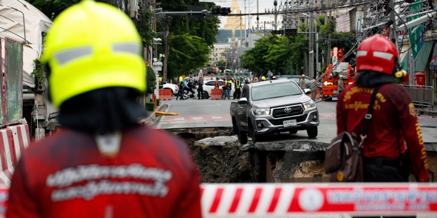 Thailändische Rettungskräfte inspizieren nach einem Strasseneinsturz in Bangkoks Bezirk Samsen ein rund 50 Meter tiefes Loch, 30 Meter breit und 30 Meter lang.