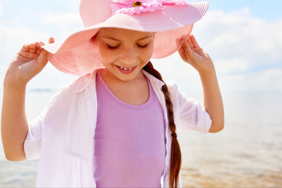 Fröhliches Mädchen mit Sonnenhut am Strand