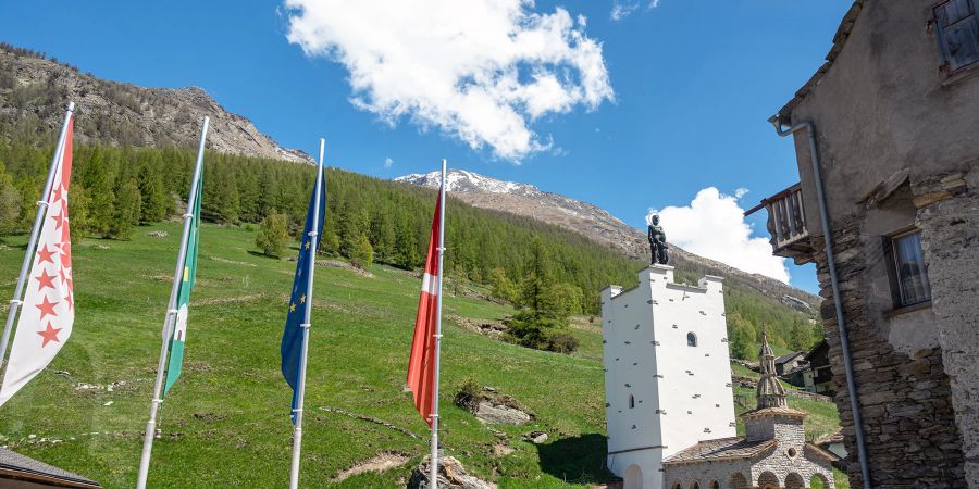 Postautohaltestelle im Dorfzentrum von Saas-Grund mit der Friedhofskapelle der Pfarrei St. Bartholomäus.
