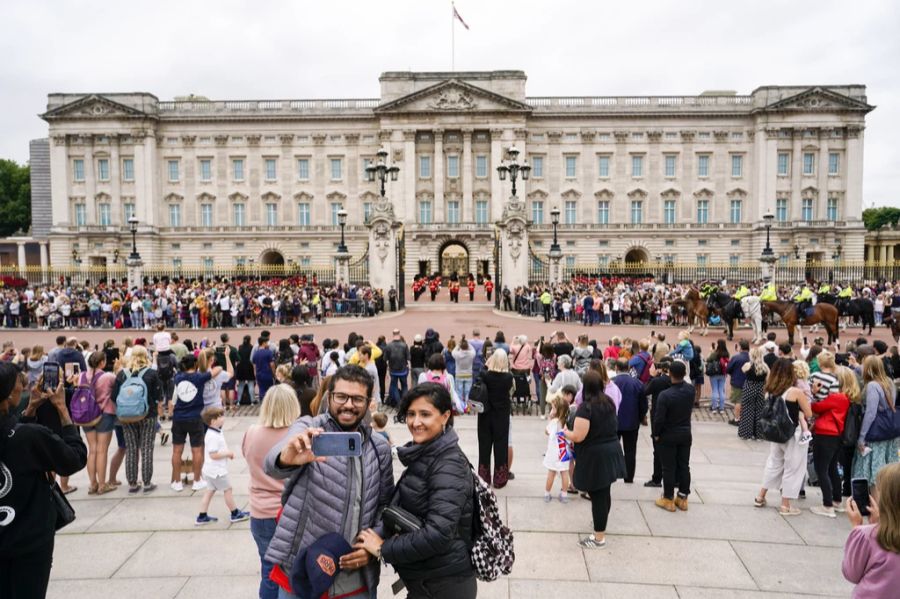 Touristen machen ein Selfie vor dem Palast in London.