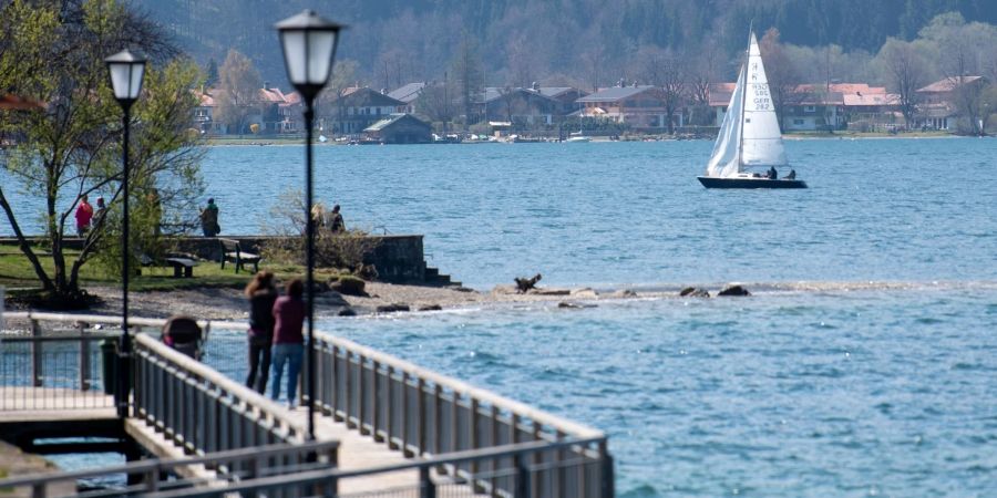 Ein Segelboot fährt in der Sonne über den Tegernsee.