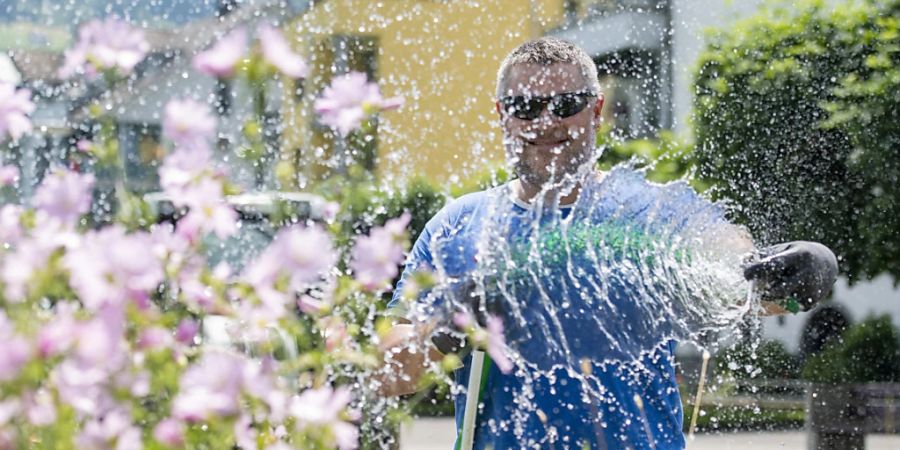 Der Gemeindearbeiter Adrian Tresch bewässert wegen der grossen Hitze Blumenkisten in der Gemeinde Buochs im Kanton Nidwalden. In einigen Gemeinden wie in Courtételle (JU) und in Mendrisio (TI) ist die Bewässerung von Rasen mit Trinkwasser wegen des fehlenden Wassers untersagt worden.