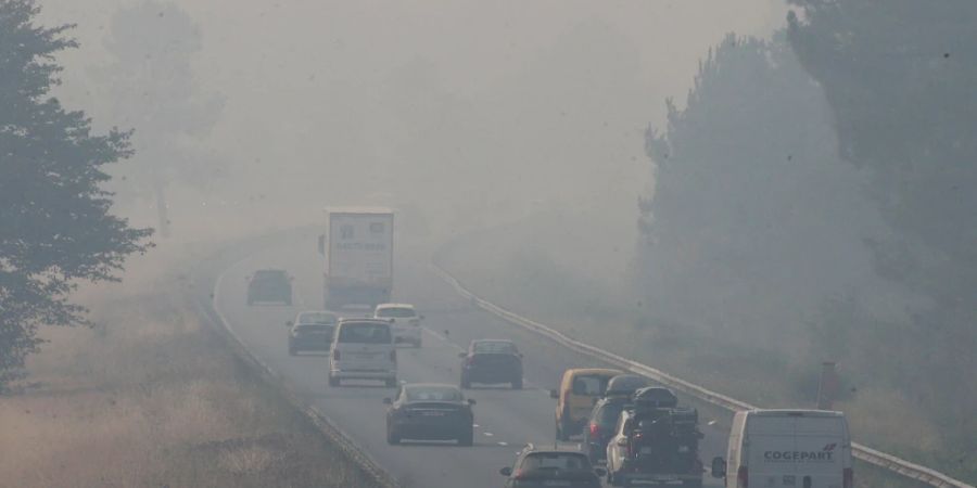 Lastwagen und Autos fahren auf der Autobahn A63, die durch einen Waldbrand 50 Kilometer südlich von Bordeaux verraucht ist. Hohe Waldbrandgefahr herrscht weiter auch in Südfrankreich. Foto: Bob Edme/AP/dpa