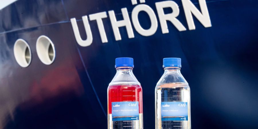 Flaschen mit herkömmlichen Diesel-Treibstoff (l) und dem im neuen Forschungsschiff «Uthörn» genutzten Methanol-Treibstoff stehen vor dem Schiff.