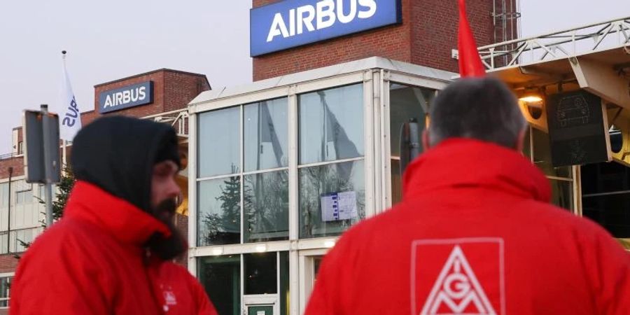 Mitglieder der IG Metall stehen vor einem Werkstor von Airbus in Hamburg-Finkenwerder. Foto: Bodo Marks/dpa