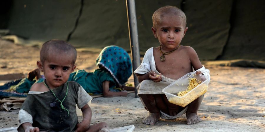 Kleinkinder, die durch die Überschwemmungen des Monsuns vertrieben wurden, essen in einem provisorischen Zeltlager für Flutopfer im pakistanischen Sukkur.