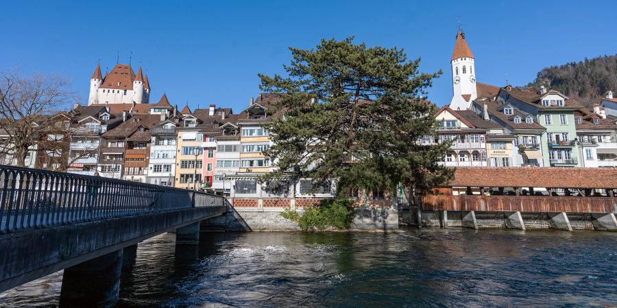 Blick auf das Schloss Thun, die Altstadt von Thun und die Stadtkirche Thun. Im Vordergrund die Mühlegässlibrücke, die Aare und die untere Schleuse.