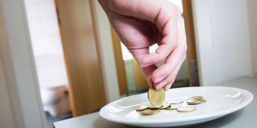 Ein Frau legt auf einer Toilette ein 50-Cent-Stück auf einen Teller: Die Geschäftsführerin eines Reinigungsunternehmens soll bei der Steuererklärung 1,2 Millionen Euro unterschlagen haben, die Toilettenbenutzer gezahlt haben.