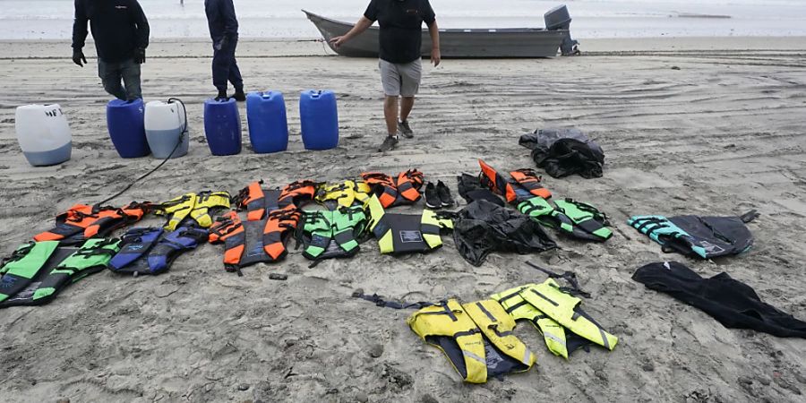 Die Bootsretter Robert Butler (r) und KC Ivers (l) sammeln Rettungswesten und Kanister vor einem der beiden Boote am Blacks Beach. Bei einem Bootsunglück vor der südlichen Küste des US-Bundesstaates Kalifornien sind mehrere Menschen ums Leben gekommen. Foto: Gregory Bull/AP