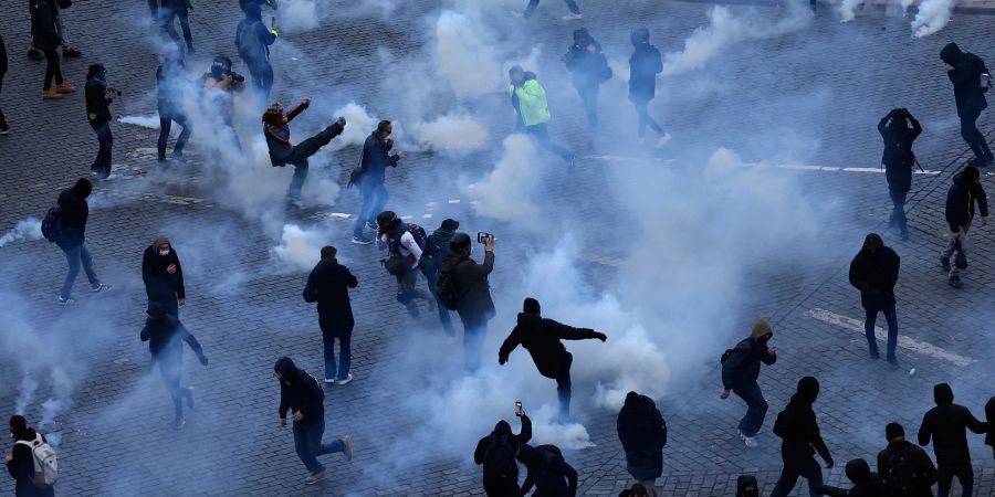 Demonstranten treten während des Protestes in Paris Tränengaskanister weg.