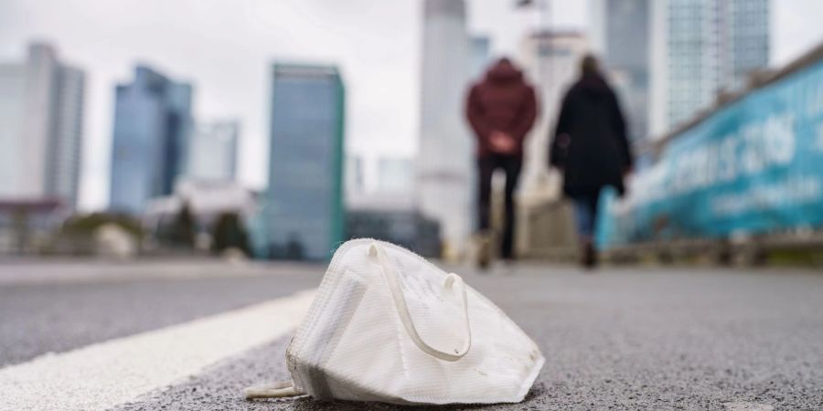 Eine FFP2-Maske liegt auf dem Gehweg der Frankfurter Untermainbrücke.