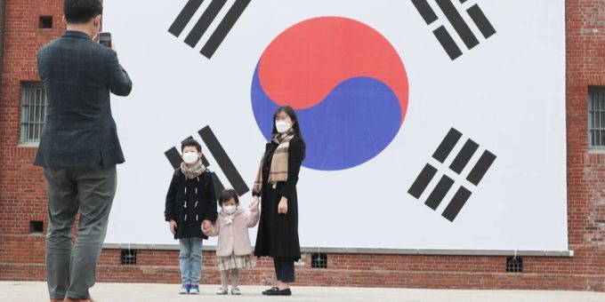 Eine Familie macht ein Foto vor einer grossen südkoreanischen Flagge in Seoul. südkorea familie