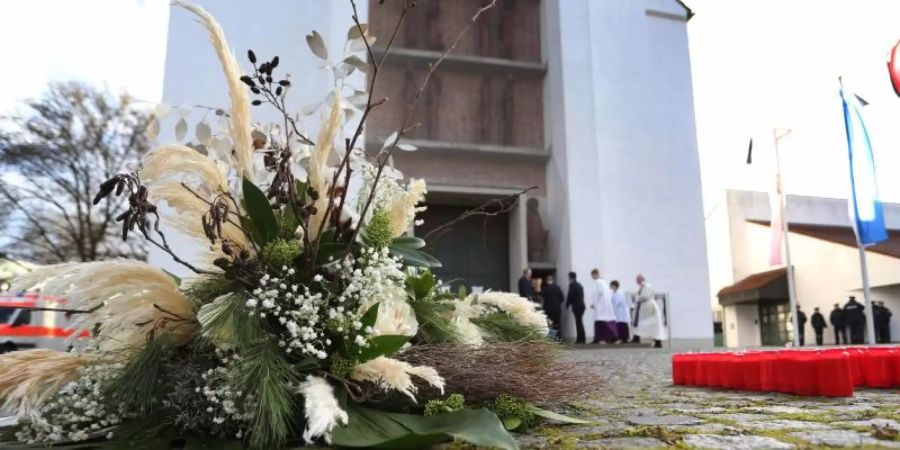 Ein Blumengebinde liegt vor der Kirche in Neusäss bei Augsburg. Foto: Karl-Josef Hildenbrand/dpa