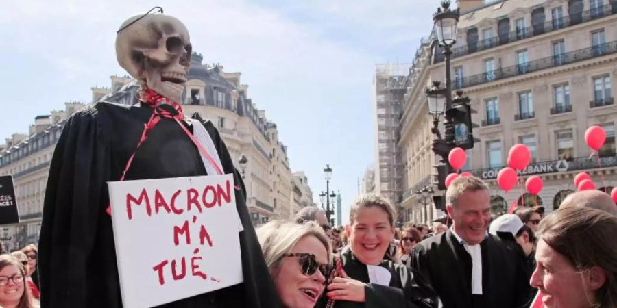 Protest in Paris: Ein Skelett in einer Richterrobe und einem Schild mit der Aufschrift «Macron hat mich getötet». Foto: Michel Euler/AP/dpa