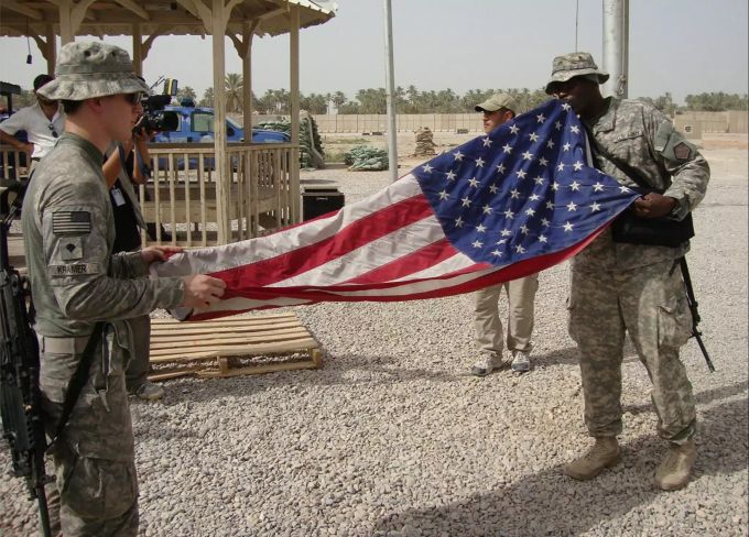 US-Soldaten falten im Militärstützpunkt Scania ihre Flagge zusammen. US-Soldaten im Irak