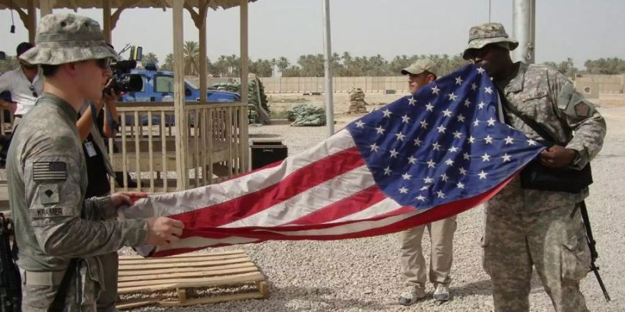 US-Soldaten falten im irakischen Militärstützpunkt Scania ihre Flagge zusammen. Foto: Khider Abbas/epa/dpa/Archiv