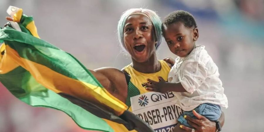 Sprint-Weltmeisterin Shelly-Ann Fraser-Pryce feiert ihren Erfolg mit ihrem Sohn Zyon auf dem Arm. Foto: Michael Kappeler/dpa