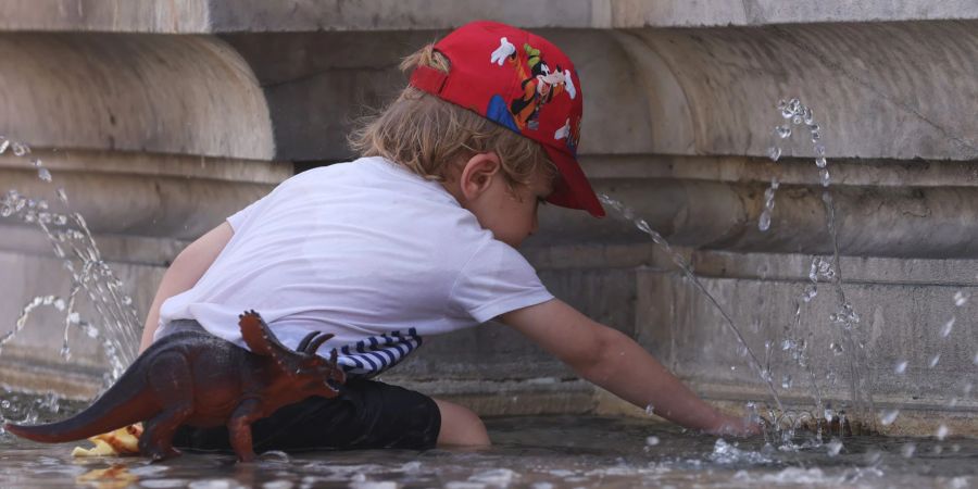 Ein Kind kühlt sich bei 38 Grad Celsius an einem Brunnen ab.