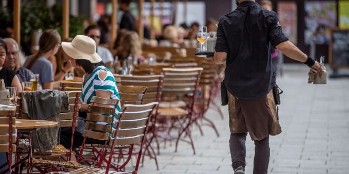 Eine Servicekraft bedient im Aussenbereich eines Restaurants die Gäste. fachkräftemangel