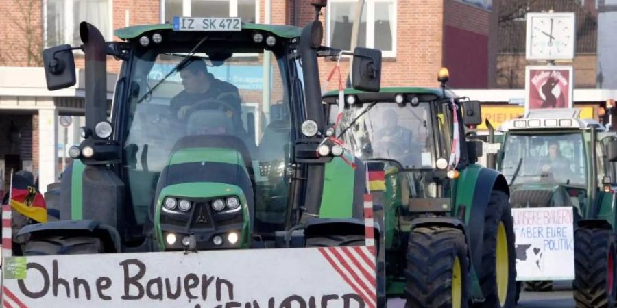 Schlagendes Argument: Landwirte nach einer Sternfahrt in Kiel. An einem Trecker warnt ein Schild mit der Aufschrift «Ohne Bauern KEIN BIER». Foto: Carsten Rehder/dpa