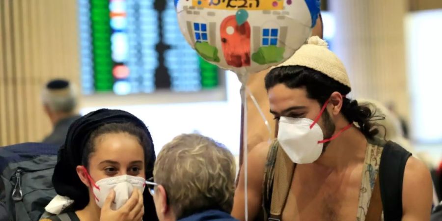 Reisende mit Schutzmasken am Flughafen von Tel Aviv