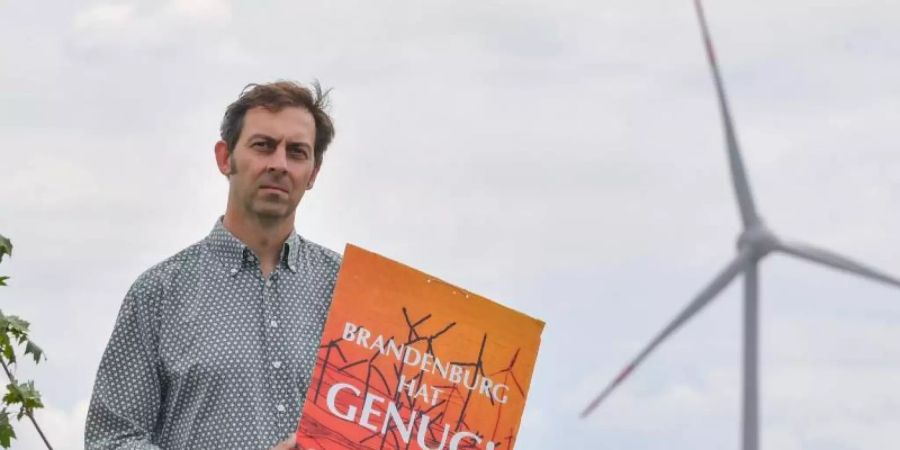 Eigenheimbesitzer Stefan Hellert auf seinem Grundstück. In rund 1500 Metern Entfernung dreht sich der Rotor einer Windenergieanlage. Foto: Patrick Pleul/zb/dpa