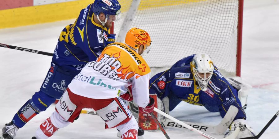 Der Rapperswiler PostFinance TopScorer Kevin Clark, M;itte, testet bewacht vom Davoser Marc Aeschlimann den Davoser Torhueter Joren Van Pottelberghe, beim Eishockey-Qualifikationsspiel der National League zwischen dem HC Davos und den SC Rapperswil Jona Lakers, am Sonntag, 09. Februar 2020 im Eisstadion in Davos. (KEYSTONE/Juergen Staiger)